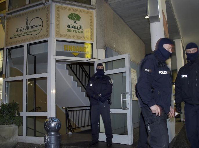 Masked police officers guard the 'Seituna' cultural center in Berlin, Germany, Thursday, Nov. 26, 2015. Police raided the mosque after the arrest of two people suspected of belonging to an Islamist extremist group. (AP Photo/Michael Sohn)