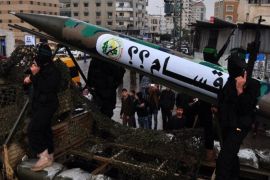 عناصر من المقاومة الفلسطينية خلال عرض عسكري سابق في غزة، يقفون بجانب صاروخ وضع عليه علامة استفهام