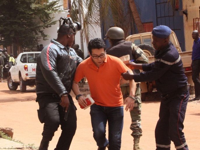 Mali trooper assist a hostage, centre, to leave the scene, from the Radisson Blu hotel to safety after gunmen attacked the hotel in Bamako, Mali, Friday, Nov. 20, 2015. Islamic extremists armed with guns and throwing grenades stormed the Radisson Blu hotel in Mali's capital Friday morning, killing at least three people and initially taking numerous hostages, authorities said. (AP Photo/Harouna Traore)