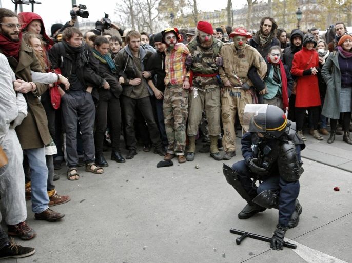 A policeman faces demonstrators after falling during an assault during a protest ahead of the 2015 Paris Climate Conference at the place de la Republique, in Paris, Sunday, Nov. 29, 2015. More than 140 world leaders are gathering for high-stakes climate talks that start Monday, and activists are holding marches and protests around the world to urge them to reach a strong agreement to slow global warming. (AP Photo/Laurent Cipriani)