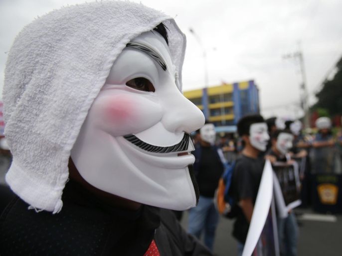 Filipino student protesters wearing masks are blocked by police as they tried to get near the House of Representatives in suburban Quezon city, north of Manila, Philippines on Tuesday Nov. 5, 2013. Supporters of hacker group Anonymous Philippines held the rally to call for the abolition of all forms of "pork barrel" funds after allegations that several members of the House of Representatives and the Philippine Senate conspired with wealthy businesswoman Janet Lim Napoles to steal huge amounts of government development funds. Napoles is set to appear before the Senate Blue Ribbon Committee on Nov. 7. (AP Photo/Aaron Favila)