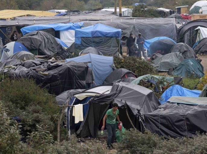 Migrants walk near tents in the "New Jungle" make-shift camp as unseasonably cool temperatures arrive in Calais, northern France, October 15, 2015. More than 3,500 people, migrants and refugees are camped in Calais, fleeing war and poverty in the Middle East, Africa and Asia and now living in the jungle. Most of them are hoping to make the crossing to England. REUTERS/Philippe Wojazer
