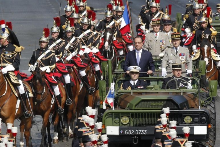 French President Francois Hollande, left standing in the command car, and Chief of Staff Gen. Pierre de Villiers, drive down the Champs Elysees avenue in Paris, France, as part of Bastille Day parade Tuesday, July 14, 2015 in Paris, France. French anti-terrorist forces join the traditional military parade celebrating Bastille Day, as the country's leadership tries to show its muscle against extremists abroad and at home. Mexico's president is the guest of honor at this year's event marking France's biggest holiday. (AP Photo/Michel Euler)