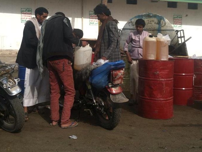 سوق سوداء للوقود في صنعاء تبيع البنزين بأسعار مضاعفة للمواطنين وتبدو شعارات الحوثيين في الخلف (الجزيرة نت)