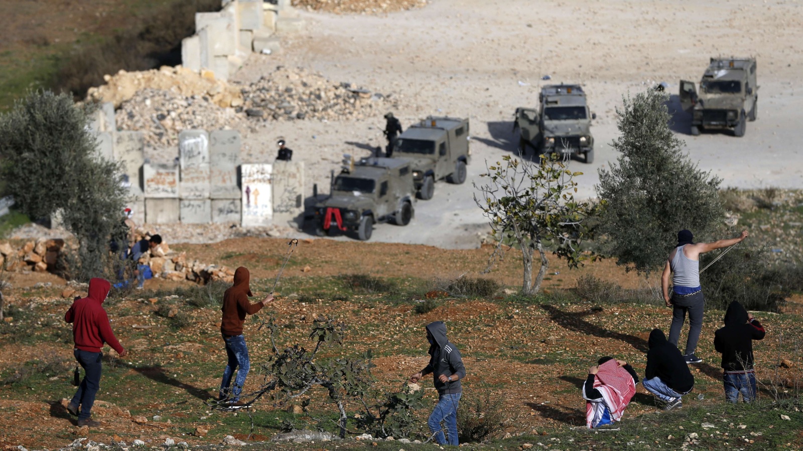 شبان فلسطينيون يقذفون عربات جيش الاحتلال بالحجارة بالقرب من سجن عوفر في بلدة بيتونيا (الفرنسية)