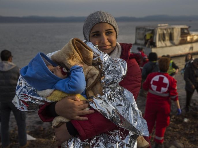 A Syrian woman holds her baby after their arrival on a small boat from the Turkish coast on the northeastern Greek island of Lesbos Monday, Nov. 16, 2015. Greek authorities say 1,244 refugees and economic migrants have been rescued from frail craft in danger over the past three days in the Aegean Sea, as thousands continue to arrive on the Greek islands. (AP Photo/Santi Palacios)