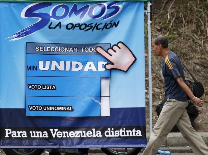 A man walks past a campaign billboard of MIN Unity Party in Caracas November 19, 2015. Venezuela's election board on Thursday banned advertisements by a small political party whose slogans mimic the main opposition coalition in what critics say is part of a campaign by the government to tilt next month's parliamentary election. Controversy has swirled for weeks around the MIN Unity party, whose name, symbols and slogans are similar to the opposition coalition Democratic Unity, which says it is an obvious attempt to confuse voters. REUTERS/Carlos Garcia Rawlins