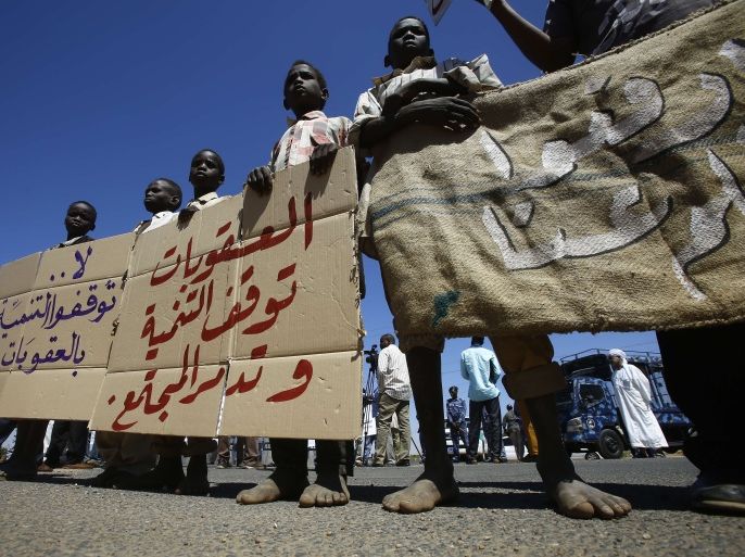 SUDAN : Sudanese children hold banners outside the US embassy in the capital Khartoum on November 3, 2015, to protest against sanctions imposed on their country by the United States. Soudan has been under a US trade embargo since 1997 imposed over rights abuses and support for radical Islamist groups in the early 1990s. The banner in the middle reads in Arabic " Sanctions halt development and destroys the society" AFP PHOTO / ASHRAF SHAZLY