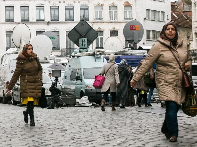 Women walk by TV satellite cars on the market square in the Molenbeek neighborhood in Brussels on Tuesday, Nov. 17, 2015. France has demanded that its European partners provide support for its operations against the Islamic State group in Syria and Iraq and other security missions in the wake of the Paris attacks. (AP Photo/Leila Khemissi)