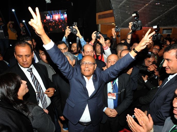 Former Tunisian president Moncef Marzouki (C) flashes the sign for victory amid his supporters during a rally to launch his new political party Al-Irada (the will) in the capital Tunis on December 20, 2015. Marzouki, a 70-year-old neurologist and founder of the Congress for the Republic party during Ben Ali's long dictatorship, has warned of a "catastrophic" situation in his country, plagued by poverty and jihadists, as he launched a new party a year after his election defeat. AFP PHOTO / FETHI BELAID