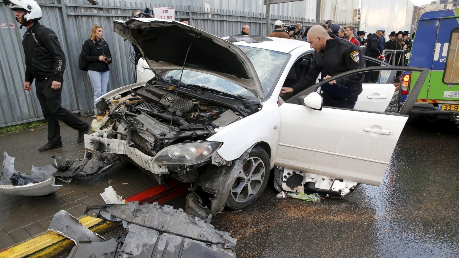 عنصر أمن إسرائيلي يتفقد سيارة استخدمها فلسطيني لدعس إسرائيليين بالقدس (رويترز)