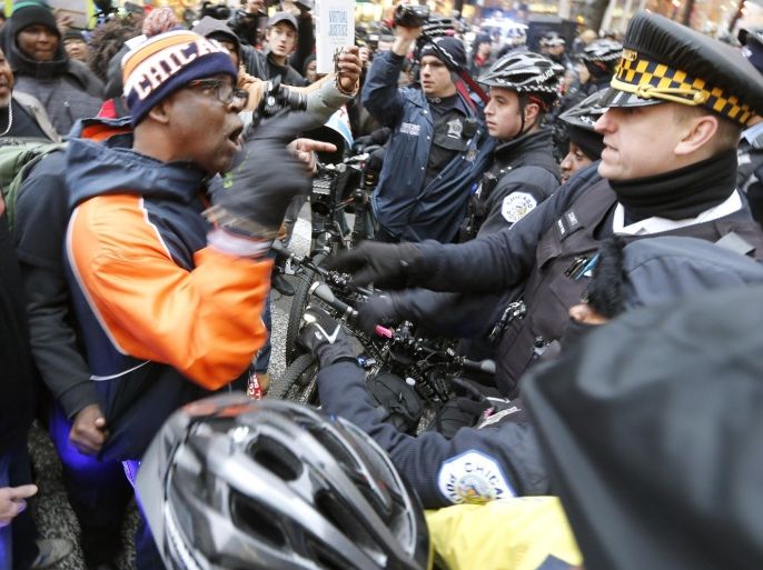 A protesters yells at a Chicago Police officer at a bicycle barricade on Chicago's Magnificent Mile Thursday, Dec. 24, 2015, in Chicago. The Christmas Eve Day protest calling for the resignation of Mayor Rahm Emanuel is the latest in a series of demonstrations in the city since the release last month of police video showing a white officer shoot a black teenager 16 times. (AP Photo/Charles Rex Arbogast)