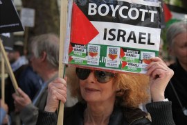 روثي اسرائيلية لاجئة في بريطانيا تحمل علم فلسطين وعليه ملصقات تطالب بمقاطعة البضائع الاسرائلية