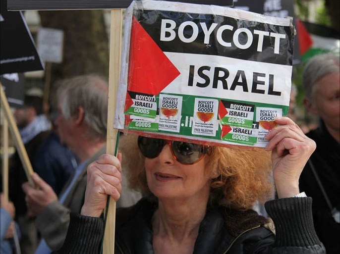 روثي اسرائيلية لاجئة في بريطانيا تحمل علم فلسطين وعليه ملصقات تطالب بمقاطعة البضائع الاسرائلية