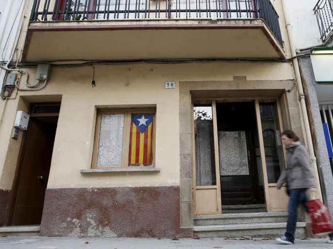 A woman walks past a house with an "Esteladas" (Catalan separatist flags) in a window in Arenys de Munt town, near Barcelona, Spain, December 9, 2015. Arenys de Munt was the first town to celebrate a non-binding referendum regarding Catalunya's independence on September 13, 2009. REUTERS/Albert Gea