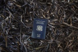 In this Thursday, Oct. 8, 2015 photo a Syrian passport found on the road that runs along the north of the Greek island of Lesbos is placed to be portrayed on a beach next to the town of Skala Sikaminias, on the northeastern Greek island of Lesbos. (AP Photo/Santi Palacios)