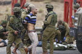 FILE - In this Wednesday, Oct. 7, 2015 file photo, Israeli soldiers arrest a man while others treat Palestinians wounded during clashes with the Israeli military, near Ramallah, West Bank. (AP Photo/Majdi Mohammed, File)