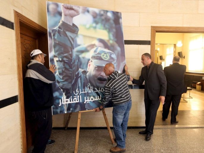 Men place a picture of Lebanese Hezbollah militant leader Samir Qantar, who was killed in an Israeli air strike in Damascus early on Sunday, in Beirut's southern suburbs where his relatives are accepting condolences for his death, December 20, 2015. REUTERS/ Hasan Shaaban