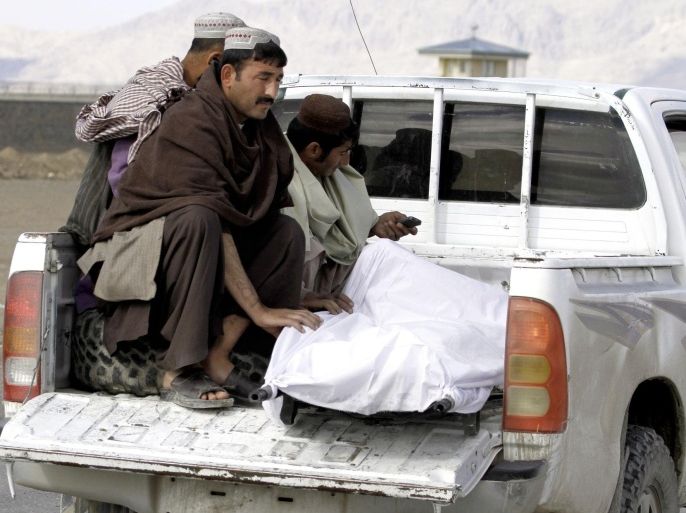 Afghan men move the dead body of a man after clashes between Taliban fighters and Afghan forces in Kandahar Airfield, Afghanistan, Wednesday, Dec. 9, 2015. A Taliban assault on an airport in the southern Afghan city of Kandahar that has been underway for nearly 24 hours has killed dozens of people, the Defense Ministry said Wednesday. (AP Photos/Allauddin Khan)