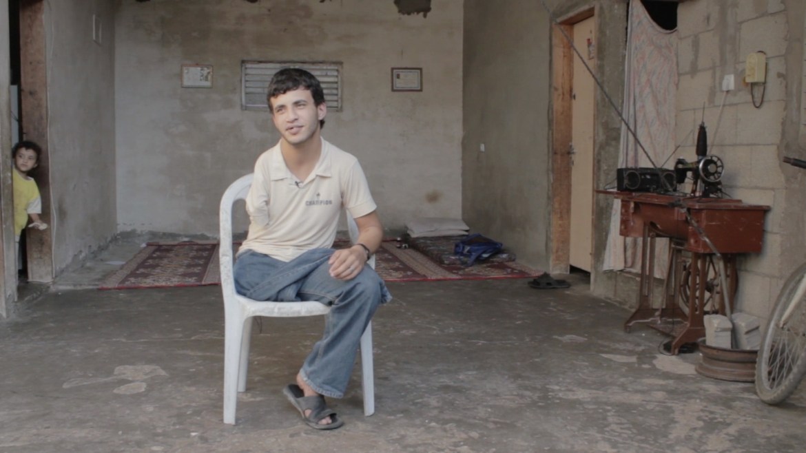 عبد الرحمن يجلس على كرسي وسط بيته المتواضع- فلسطين تحت المجهر