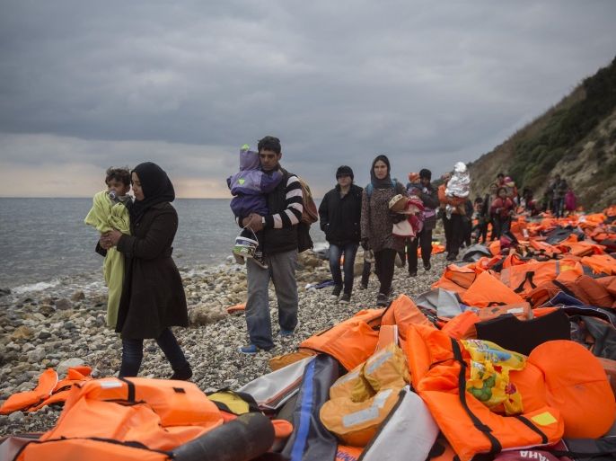 Refugees and migrants walk along a beach after crossing a part of the Aegean on a dinghy, from Turkey to the Greek island of Lesbos, on Saturday, Dec. 12, 2015. Any link between extremism and the thousands of people fleeing violence in Syria and elsewhere is false, a top European human rights official said Friday, noting that those who have perpetrated recent attacks in Europe were citizens of European countries.(AP Photo/Santi Palacios)