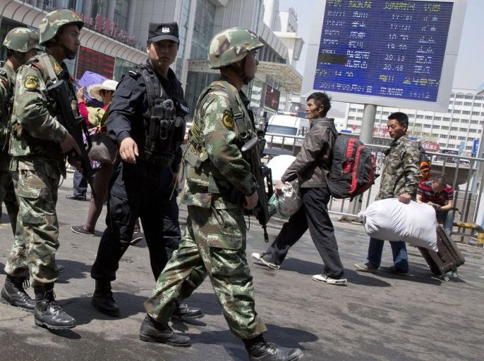 In this Thursday, May 1, 2014 file photo, armed Chinese paramilitary policemen march past the site of the explosion outside the Urumqi South Railway Station in Urumqi in northwest China's Xinjiang Uygur Autonomous Region. Beijing’s tight controls and monopoly on the narrative make it difficult to independently assess if the lethal action has been justified. And Chinese authorities prevent most reporting by foreign journalists inside Xinjiang, making it nearly impossible to confirm the state media numbers. Uighur exile groups and the U.S.-government funded broadcaster Radio Free Asia report far more violent incidents than Chinese state media do, and in some cases, higher death tolls and police shootings of Uighur protesters. But those reports are similarly hard to verify. (AP Photo/Ng Han Guan, File)