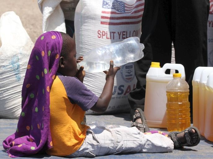 A child drinks water near the monthly food ration at a distribution center in rural Mupinga area in Chiredzi, Zimbabwe, October 6, 2015. Tens of millions of people across sub-Saharan Africa are going hungry due to erratic weather and the situation is set to worsen as the El Nino weather pattern reaches its peak, the Red Cross said on Monday as it launched funding appeals for six countries, including Zimbabwe. REUTERS/Philimon Bulawayo