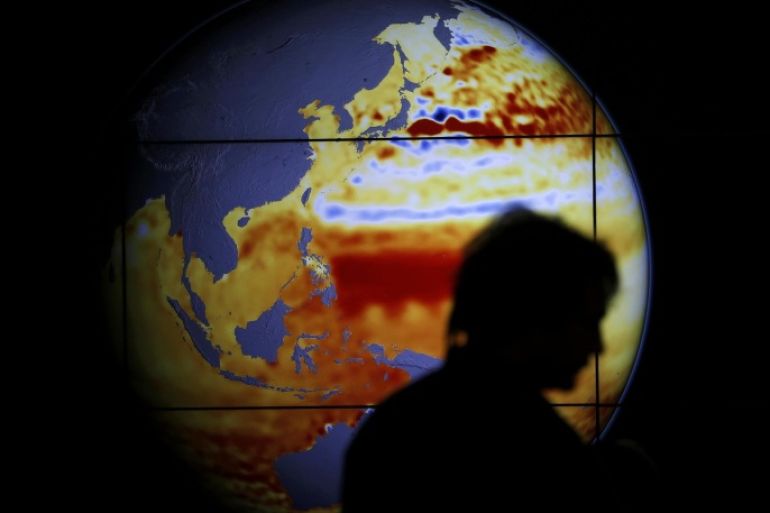 A woman walks past a map showing the elevation of the sea in the last 22 years during the World Climate Change Conference 2015 (COP21) at Le Bourget, near Paris, France, December 11, 2015. REUTERS/Stephane Mahe TPX IMAGES OF THE DAY