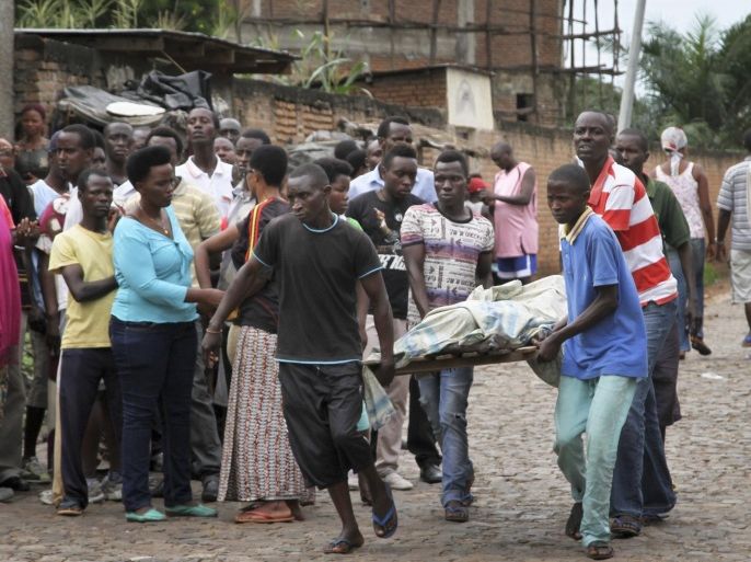 Men carry away a dead body in the Nyakabiga neighborhood of Bujumbura, Burundi, Saturday, Dec. 12, 2015. Burundi's political violence continued Saturday as a number of people were found shot dead in the Nyakabiga neighborhood of the capital, a day after the government said an unidentified group carried out coordinated attacks on three military installations. (AP Photo)