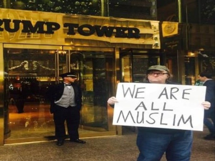 صورة المخرج الأميركي مايكل مور - من صفحته على فيسبوك وهو يحمل لافتة " كلنا مسلمون"