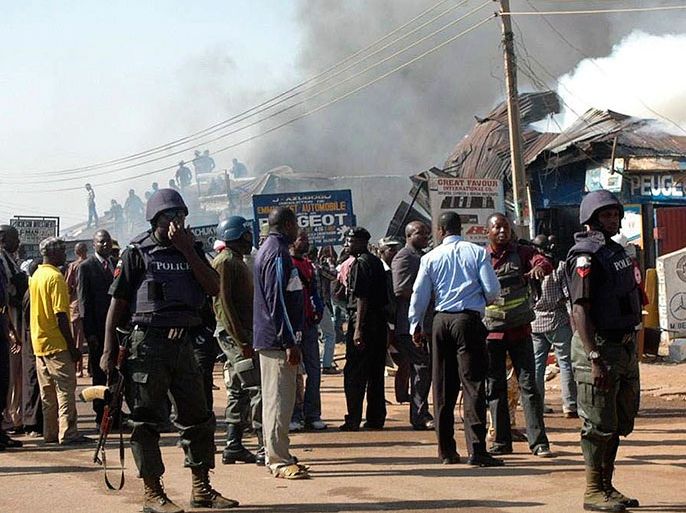 epa03026909 Nigerian police control a street shortly after a bomb blast in a market in Ogbomoshoin area of Kaduna, Nigeria, 07 December 2011. Reports state the early morning explosion in the northern city of Kaduna killed 10 people, including a pregnant woman and two children. A group suspected to be Islamist militants reportedly arrived on motorbikes and threw bombs into the crowded spare parts market. EPA/STR