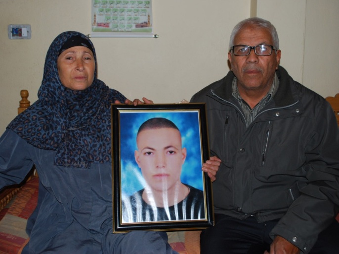 حسن وزوجته راضية يحملان صورة ابنهما أيمن الذي قتل برصاص قناص أثناء الثورة (الجزيرة نت)