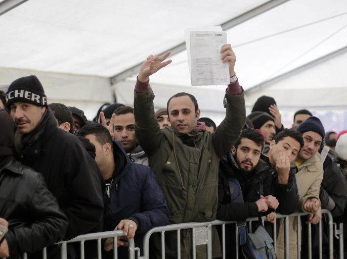 A migrant shows a document as he waits with hundreds of migrants in a tent to continue the registration process at the central registration center for refugees and asylum seekers LaGeSo (Landesamt fuer Gesundheit und Soziales - State Office for Health and Social Affairs) in Berlin, Monday, Dec. 14, 2015. (AP Photo/Markus Schreiber)