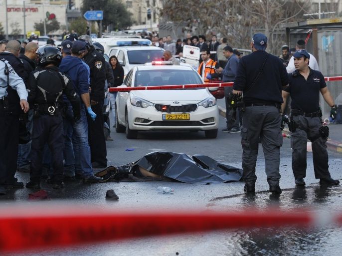 Israeli policemen stand near the covered body of a Palestinian attacker who was killed by police after he crashed his car into a bus stop in Jerusalem, Israel, 14 December 2015. A Palestinian driver in Jerusalem intentionally rammed his car into a bus stop full of people, injuring eleven Israelis, before he was shot and killed.