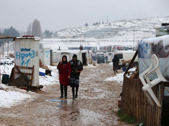 Two Syrian women from Raqqa walk through a Syrian refugee camp in the Bekaa Valley in Lebanon after the first heavy snow storm hit Lebanon, January 3, 2016.  REUTERS/Jamal Saidi