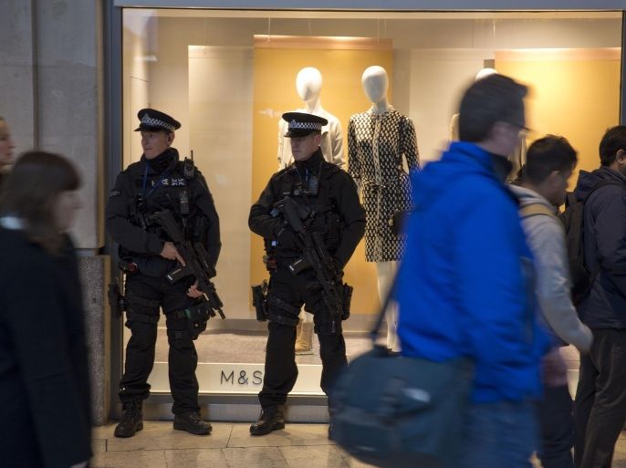 Armed British police officers stand beside a shop window inside Waterloo train station in London, Thursday, Jan. 14, 2016. UK police authorities have decided to increase the number of armed police officers on the streets of the capital following the attacks in Paris last year. (AP Photo/Matt Dunham)