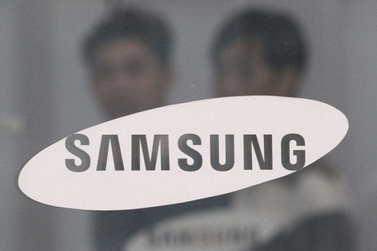 FILE - In this July 17, 2015 file photo, employees walk past a logo of Samsung Group at the head office of Samsung C&amp;T Corp. in Seoul, South Korea. South Korea's financial regulator said Friday, Dec. 4, 2015 it has launched an investigation into possible insider trading by Samsung executives related to a contentious takeover deal. (AP Photo/Ahn Young-joon, File)