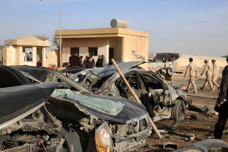 Security officers and people walk next damaged cars at the site where a truck bomb exploded at a police camp in the north-western coastal city of Zliten, Libya, 07 January 2016. At least 70 people were killed and dozens injured in the suicide bombing that occurred when a truck, packed with explosives, crashed into the gate of the camp where a crowd of policemen were gathering in the morning. Most of the casualties are believed to be policemen.
