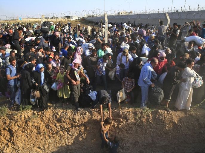 FILE - Syrian refugees walk into Turkey after breaking the border fence and crossing from Syria in Akcakale, Sanliurfa province, southeastern Turkey, Sunday, June 14, 2015. The mass displacement of Syrians across the border into Turkey comes as Kurdish fighters and Islamic extremists clashed in nearby city of Tal Abyad. (AP Photo/Lefteris Pitarakis, File)