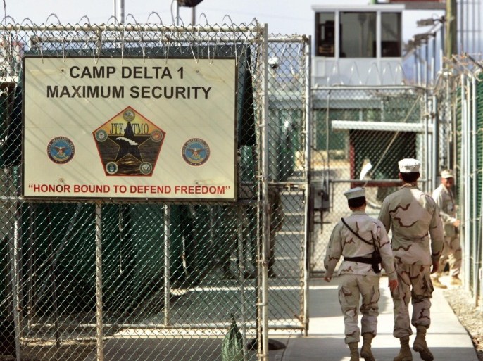 FILE - In this June 27, 2006 file photo, reviewed by a U.S. Department of Defense official, U.S. military guards walk within Camp Delta military-run prison, at the Guantanamo Bay U.S. Naval Base, Cuba. A senior U.S. official says the first of 17 detainees scheduled to be released from the Guantanamo Bay prison in January will be transferred next week, as the Obama administration continues efforts to reduce the population at the controversial detention center. (AP Photo/Brennan Linsley, File)