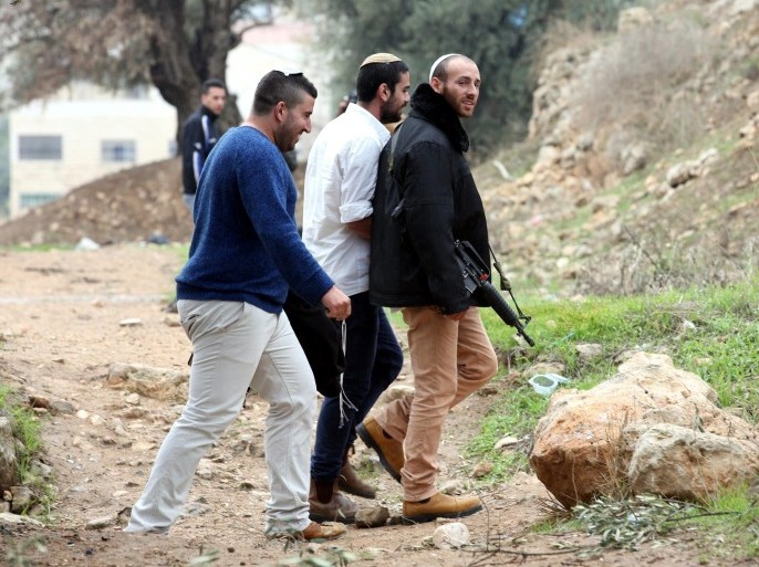 Armed Jewish settlers pass by in front of Palestinian houses in the West Bank city of Hebron, 07 November 2015. The Israeli army reportedly took over two houses and turned them into an outpost and banned their owners to leave them until they have been checked for  security missions during the Jewish Shabat holiday.