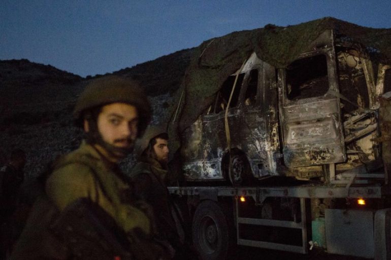 Israeli soldiers watch as a truck carries a military vehicle that was hit by a missile fired by Hezbollah on the Israel-Lebanon border, Wednesday, Jan. 28, 2015. (AP Photo/Ariel Schalit)