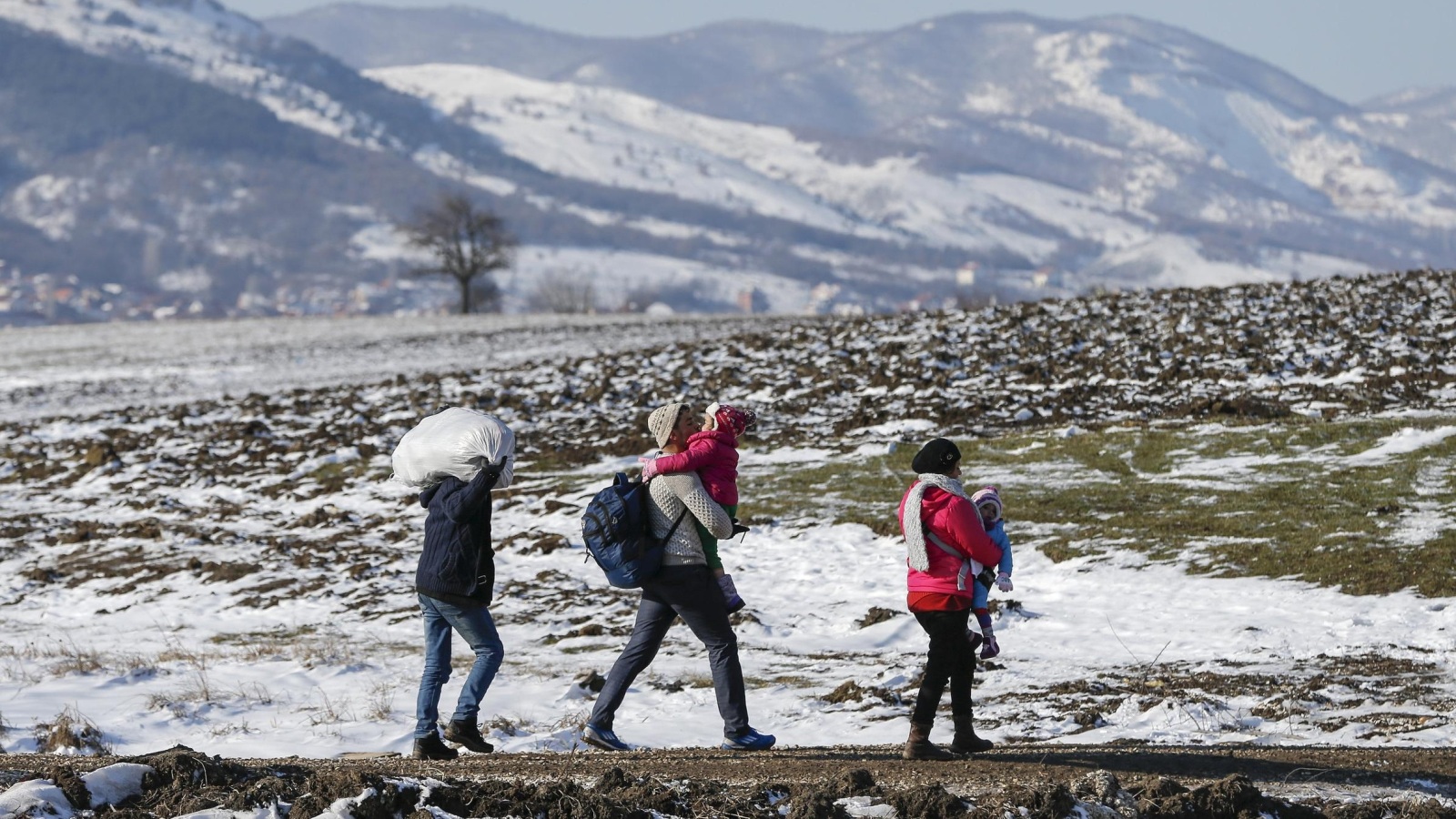 لاجئون مع أطفالهم يعبرون قرب قرية ميراتوفاك الصربية (رويترز)