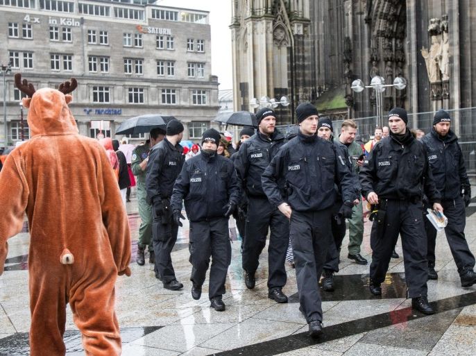 A man wearing a costume walks past members of the German police in front of the Cathedral in Cologne, Germany, 04 February 2016. The carnival peak season has begun with increased security measures in place following a string of New Year's Eve attacks when scores of women reported to have been sexually harassed and robbed at the city's main train station.
