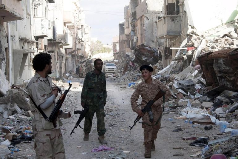 Members of Libyan pro-government forces, backed by the locals, walk with weapons during clashes in the streets with Shura Council of Libyan Revolutionaries, an alliance of former anti-Gaddafi rebels who have joined forces with Islamist group Ansar al-Sharia, in Benghazi in this April 1, 2015 file photo. Libyan soldiers had hoped for a quick victory after local residents took up arms and joined them. But 16 months later the campaign has stalled as Islamist fighters play cat and mouse with government forces -- picking them off with snipers hiding in residential buildings who are hard to hit with heavy weapons. The battle for Benghazi is typical of the chaos engulfing Libya four years after the fall of Muammar Gaddafi. To match Insight LIBYA-SECURITY/BENGHAZI REUTERS/Stringer/Files