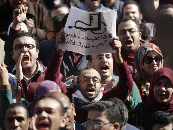 Egyptian doctors shout anti-police slogans as one holds a banner showing a police boot stepping on a medical stethoscope with Arabic slogan reading, "police are thugs," during a protest against rampant police abuses, after two doctors were beaten up by policemen in a Cairo hospital, in front of their headquarters of the Egyptian Medical Syndicate in Cairo, Egypt, Friday, Feb. 12, 2016. Doctors threatened to escalate if the government doesn’t hold police accountable for abuses. (AP Photo/Amr Nabil)