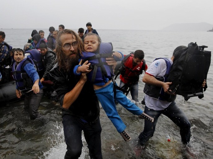 A volunteer carries a Syrian refugee child off an overcrowded dinghy at a beach after the migrants crossed part of the Aegean Sea from Turkey to the Greek island of Lesbos in this September 23, 2015 file photo. REUTERS/Yannis Behrakis/files