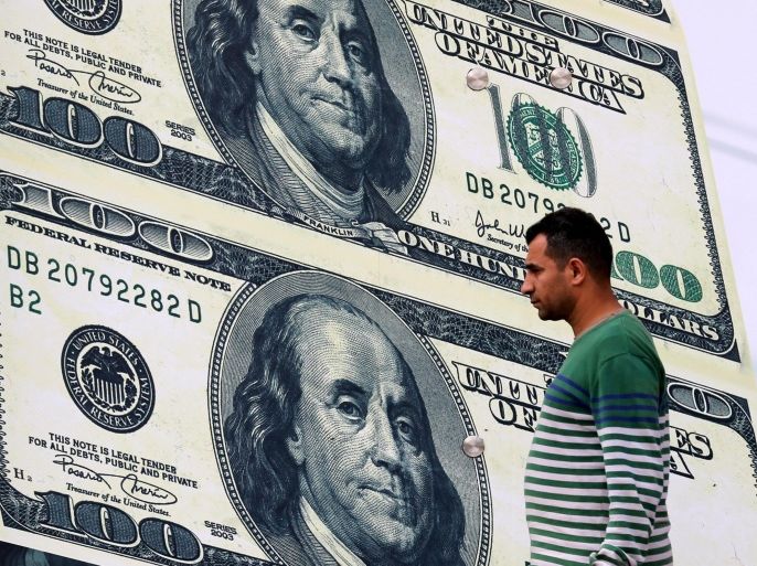 A man walks past an exchange bureau advertisement showing images of the U.S dollar in Cairo, Egypt, Feburary 21, 2016. The Egyptian pound held steady against the dollar at an official foreign currency auction on Sunday and on the black market, with traders limiting their transactions to regular clients after the central bank began cracking down on unofficial trading. REUTERS/Mohamed Abd El Ghany