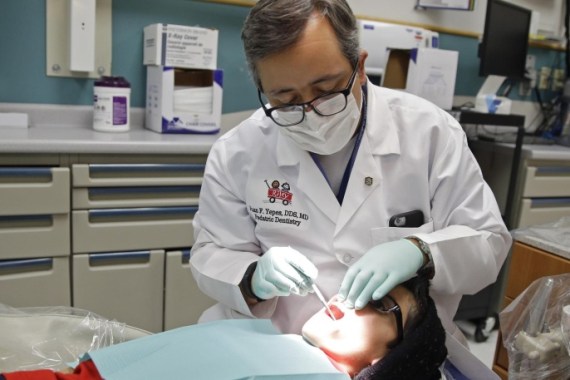 In this Friday, Jan. 22, 2016 photo, Dr. Juan Fernando Yepes, a dentist at the Riley Hospital for Children Department of Pediatric Dentistry, checks the teeth of Justin Perez, 11, during an office visit in Indianapolis. Medicaid covers dental care for an estimated 37 million children from low-income families. The state and federal Medicaid program varies by state, but there are national shortages of dentists who participate. (AP Photo/Michael Conroy)