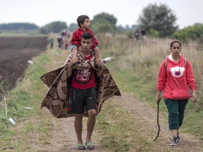 A migrant familly walks through a field after crossing into Hungary from the border with Serbia near the village of Roszke September 5, 2015. Austria and Germany threw open their borders to thousands of exhausted migrants on Saturday, bussed to the Hungarian border by a right-wing government that had tried to stop them but was overwhelmed by the sheer numbers reaching Europe's frontiers.Left to walk the last yards into Austria, rain-soaked migrants, many of them refugees from Syria's civil war, were whisked by train and shuttle bus to Vienna, where many said they were resolved to continue on to Germany. REUTERS/Marko Djurica